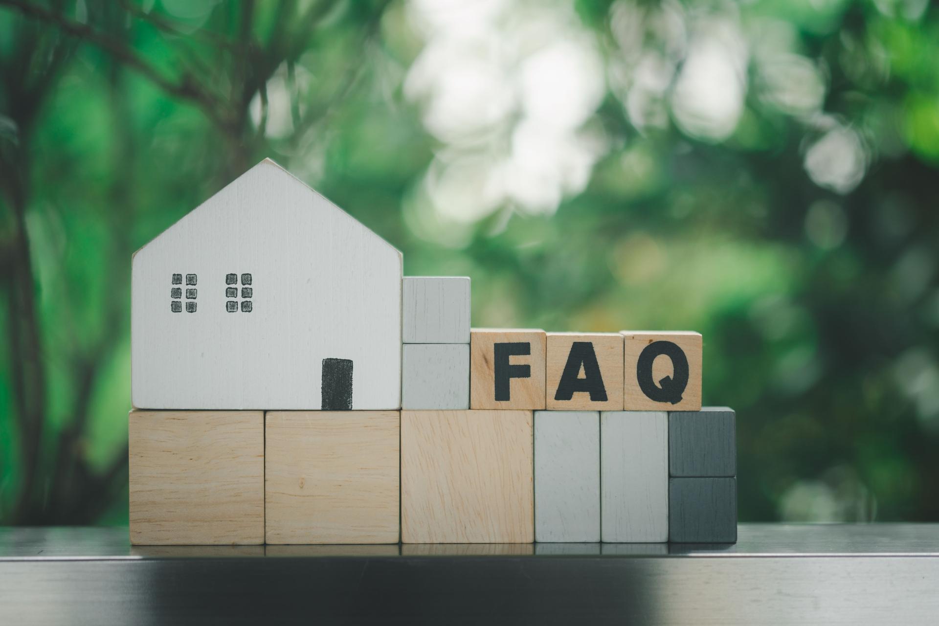 Wooden blocks with the word FAQ place with white home. The concept of FAQ about house problems. Instructions and rules on Internet sites